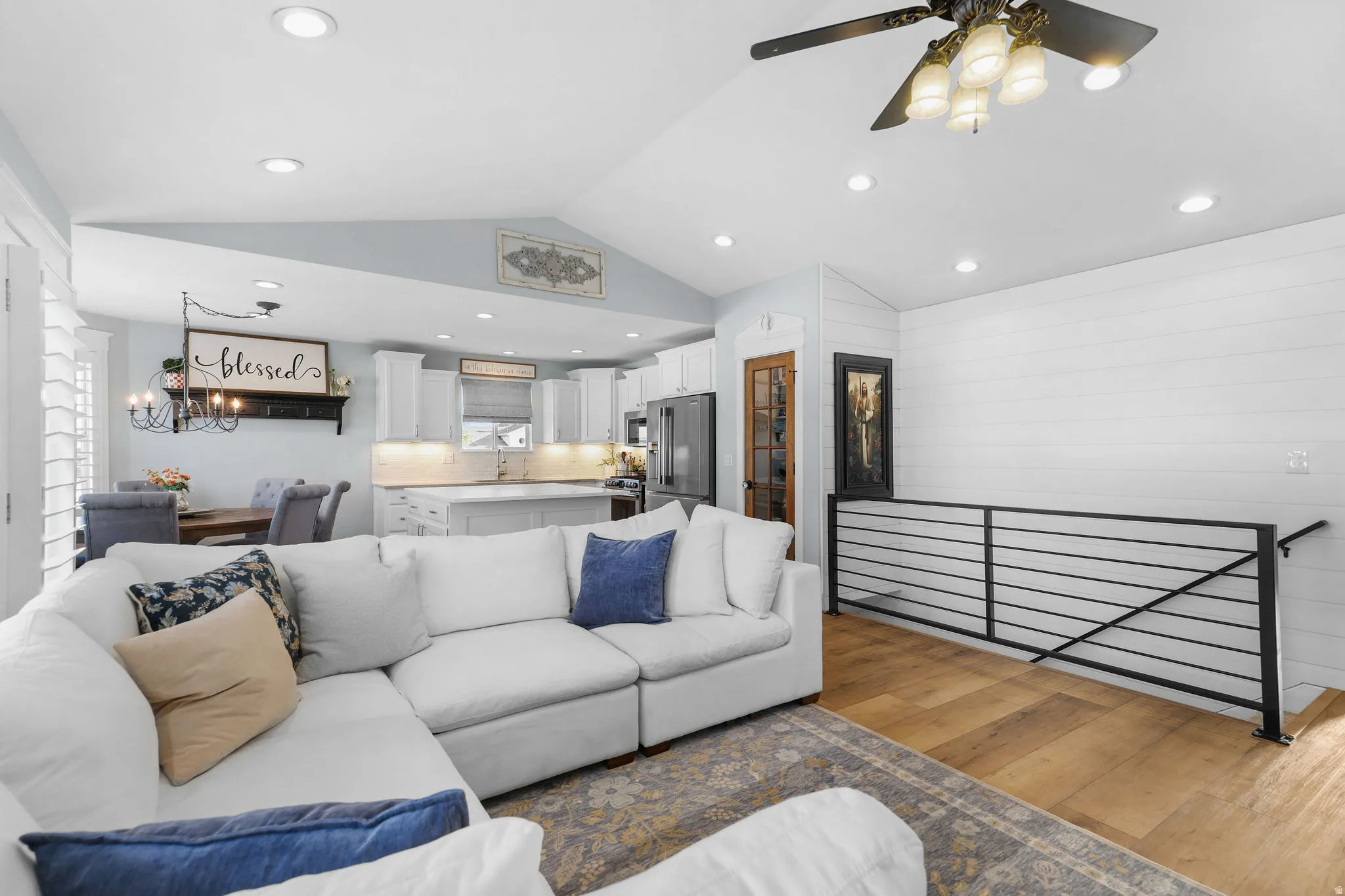 Vaulted ceiling, recessed lighting, wood-finish flooring, white shiplap wall, and contemporary black metal railing