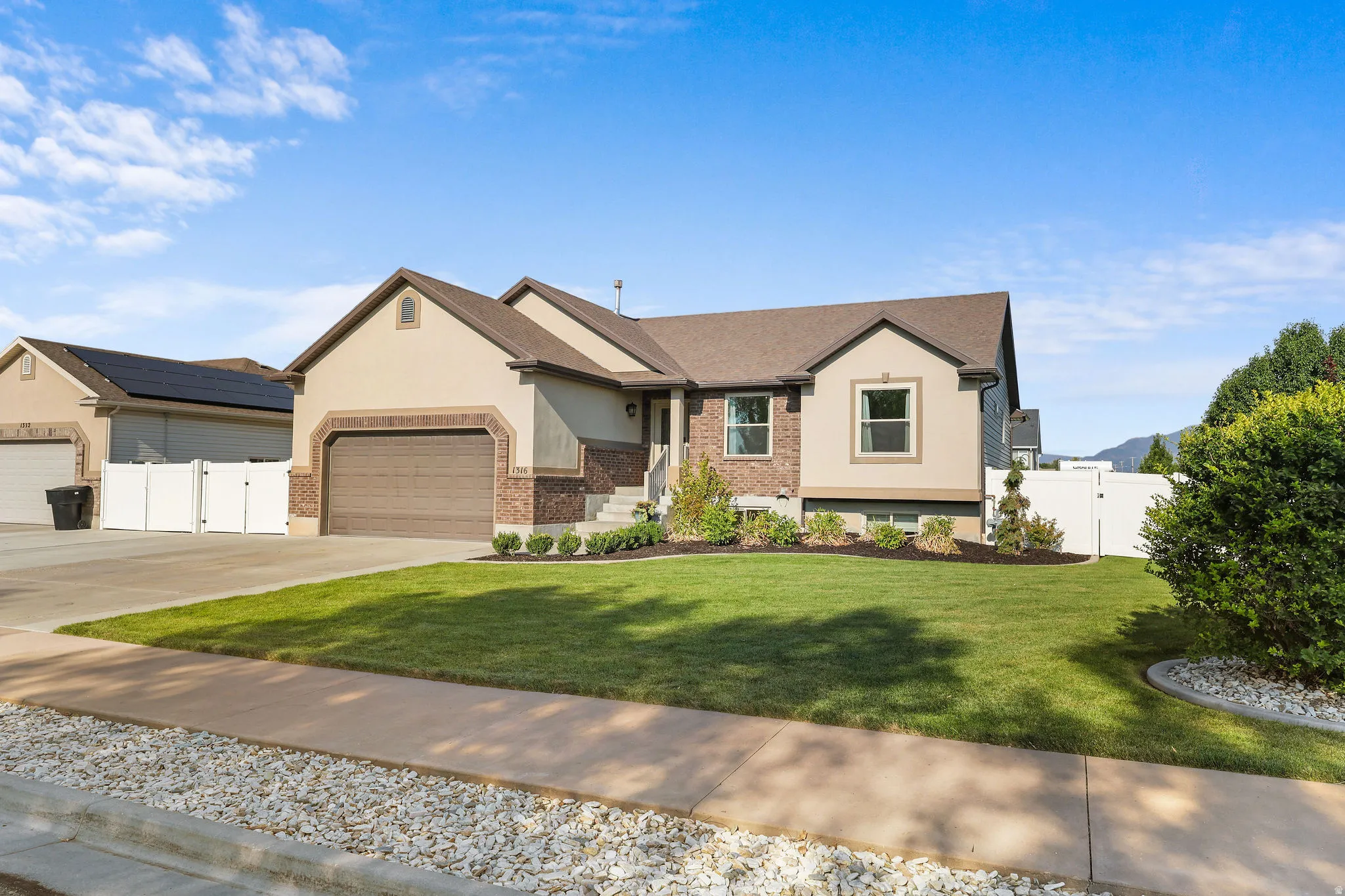 Stucco and brick facade with a brown garage door, mature landscaping, and a well-maintained lawn
