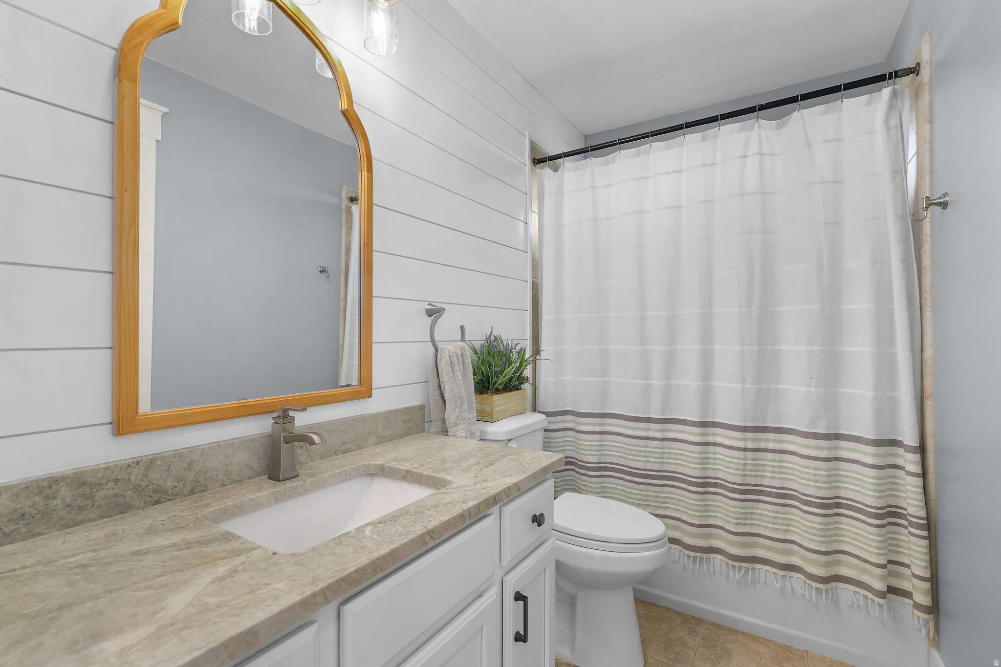 White vanity with dark hardware, undermount sink, and stone-look countertop