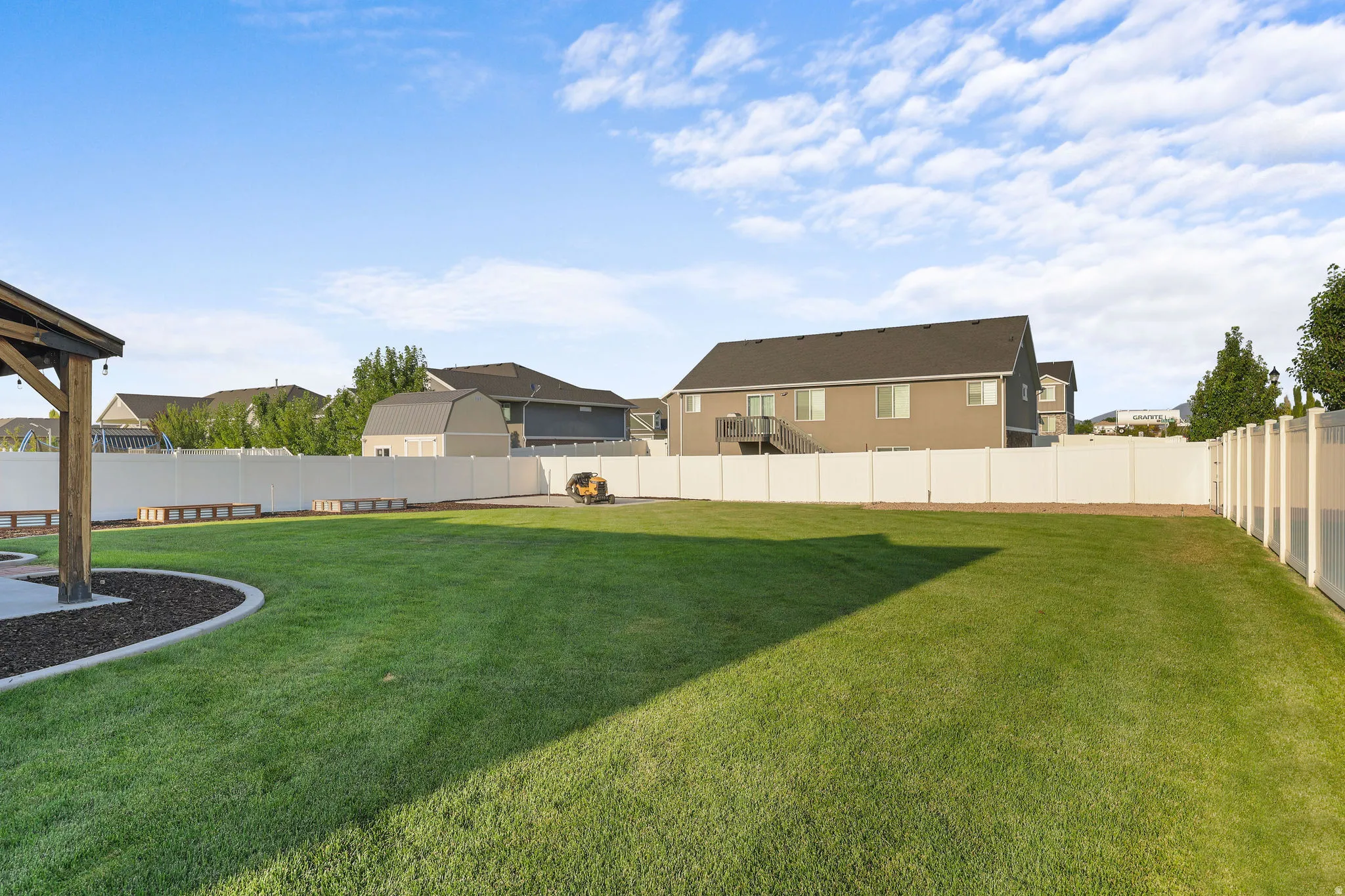 Expansive green lawn with a white privacy fence
