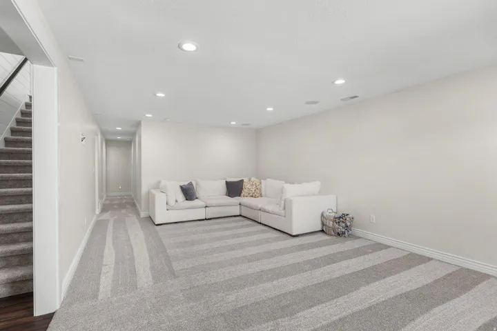 Recessed lighting, light-toned walls, and striped carpeting