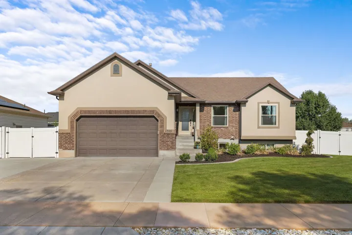 Stucco and brick exterior with a two-car garage, concrete driveway, and established front lawn