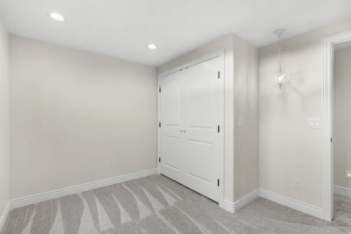 Recessed lighting, arched closet doors, crown molding, patterned carpeting, and a decorative ceiling fixture