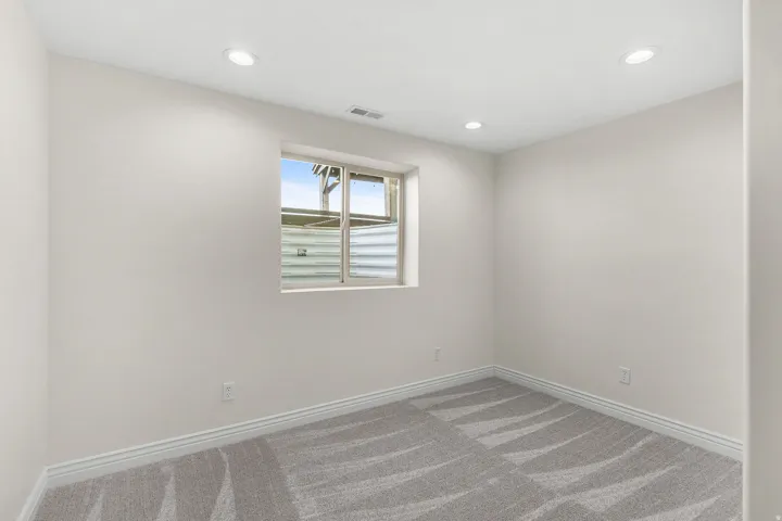 Recessed lighting, light gray walls, window, and patterned carpeting