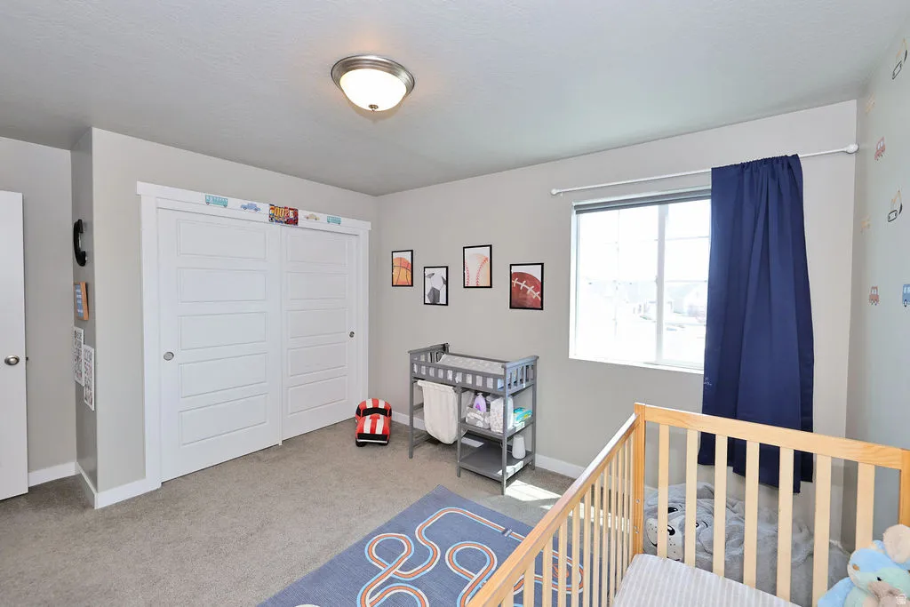 2 of 3 upstairs bedrooms Room featuring light gray walls, gray carpet flooring, a flush-mount ceiling light, and a double-pane window with a white frame