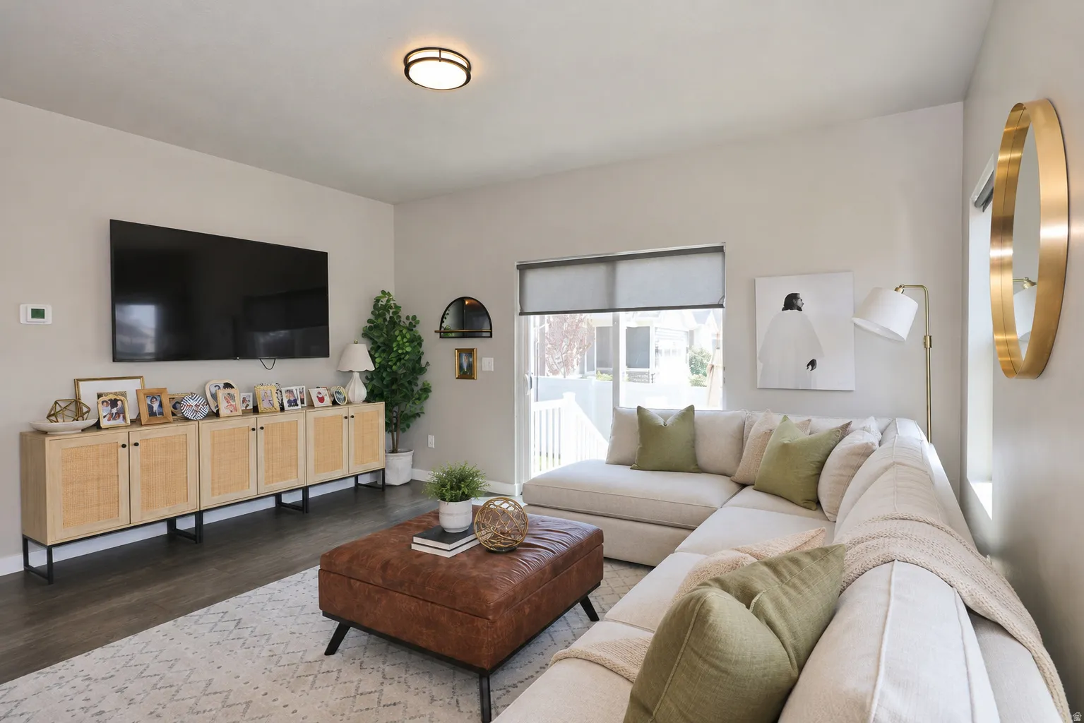 Spacious living area featuring dark wood-finish flooring, light neutral wall tones, and a contemporary flush-mount ceiling light