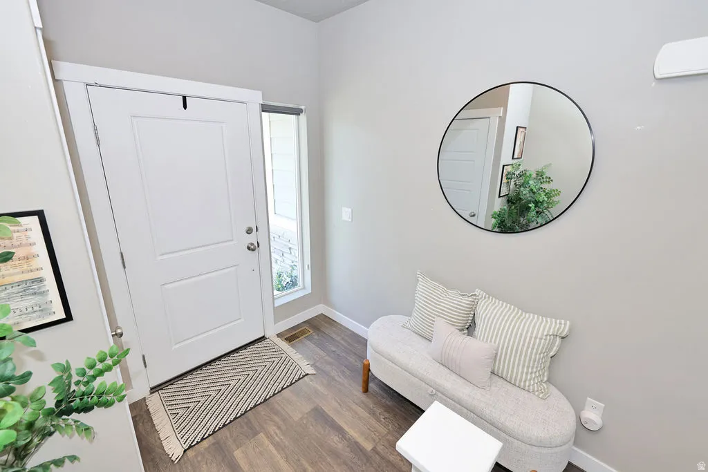 Entryway featuring wood-finish flooring, a white paneled entry door, and a full-length sidelight window