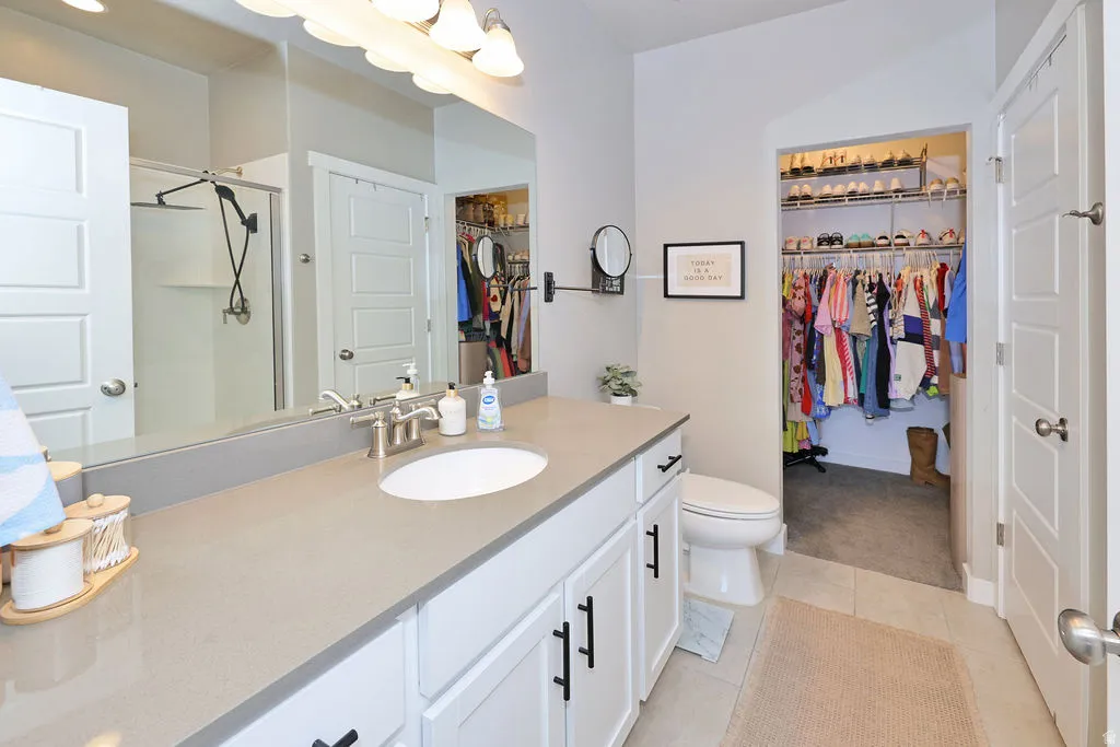Primary Bathroom vanity featuring an undermount sink, a light-toned countertop, and white cabinetry with dark hardware