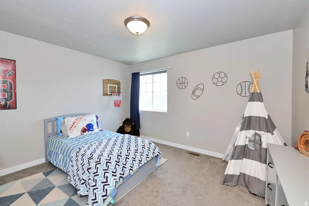 3 of 3 upstairs bedrooms spacious bedroom featuring light neutral walls, a single window with blue curtains, wall-to-wall carpeting, and a flush-mount ceiling light fixture