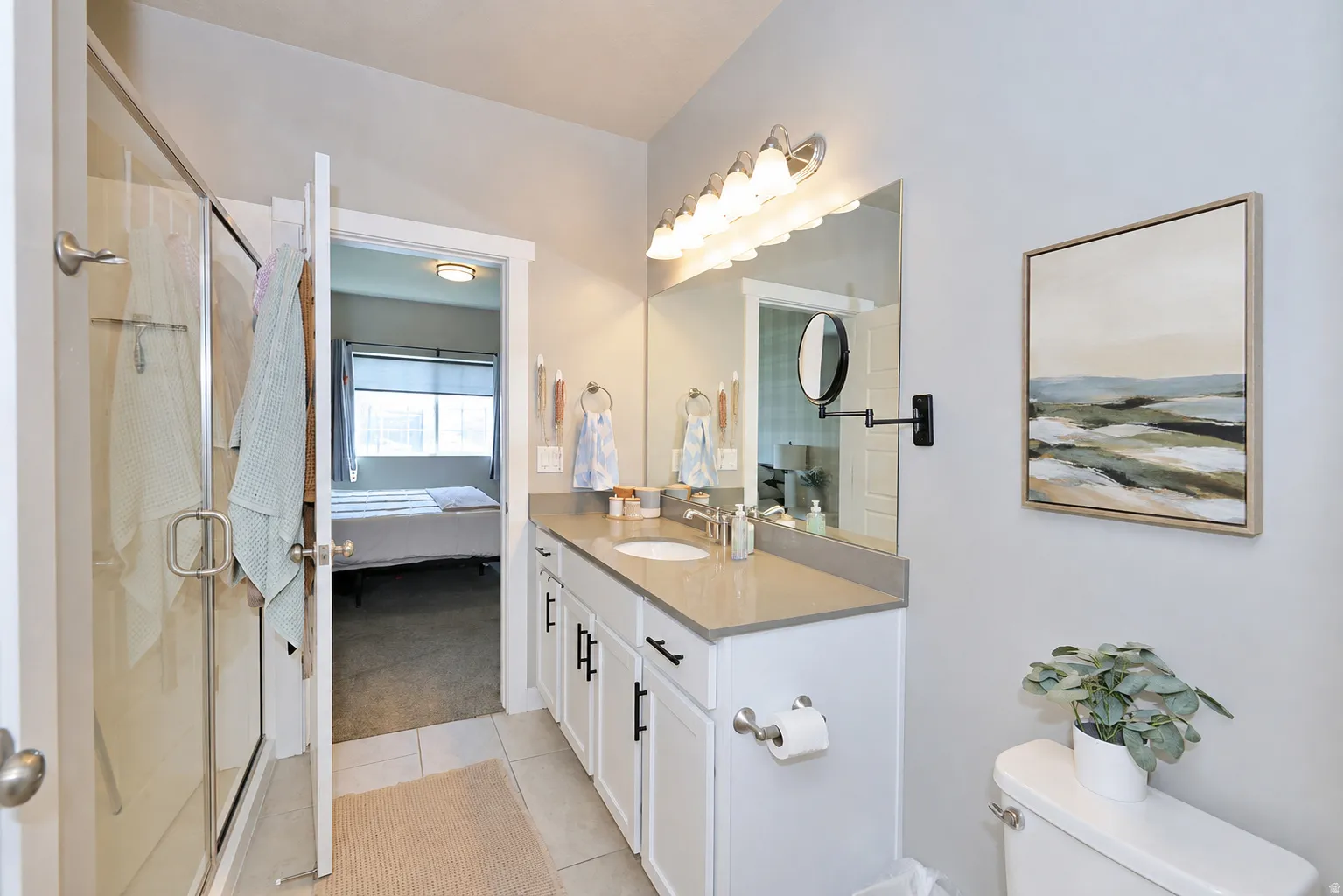 Primary bathroom White vanity with dark hardware, a single basin sink, and a light-toned countertop