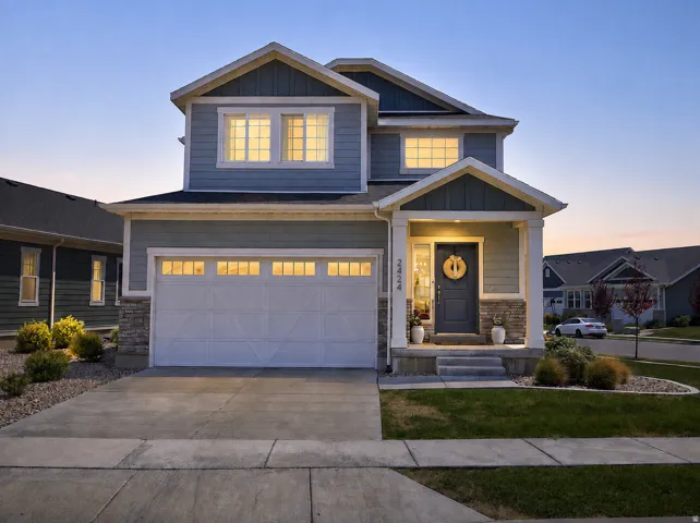 Two-story residence featuring light blue siding, stone facade accents, and a covered entry porch