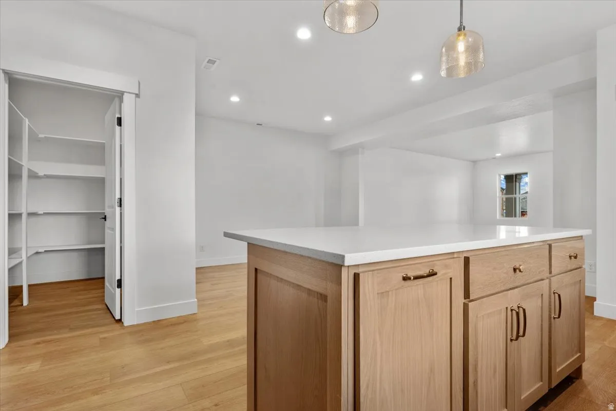 Kitchen island with a light wood-finish base, integrated storage, and a light-toned countertop