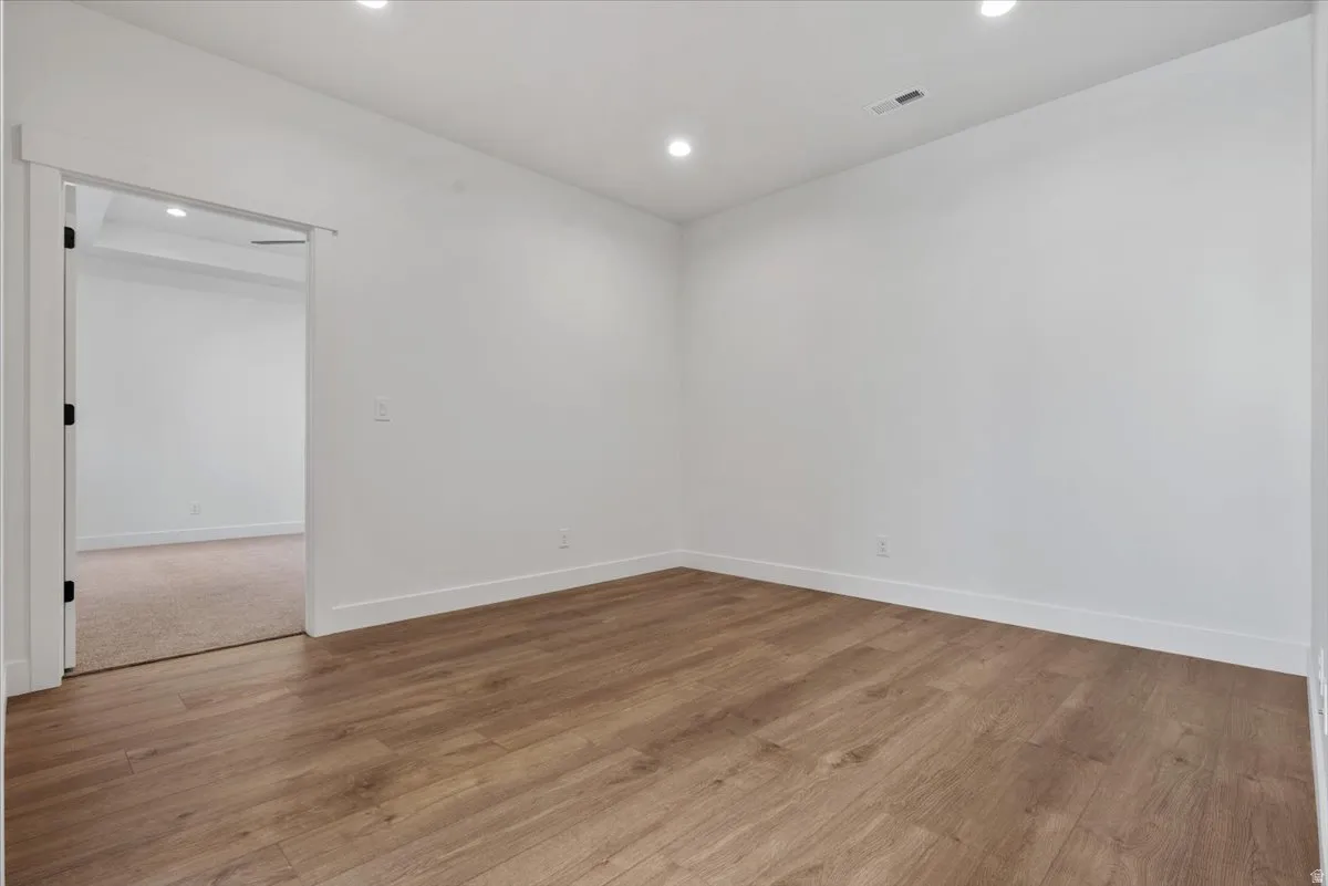 Wood-finish flooring, recessed ceiling lighting, crisp white walls, and a white trim package