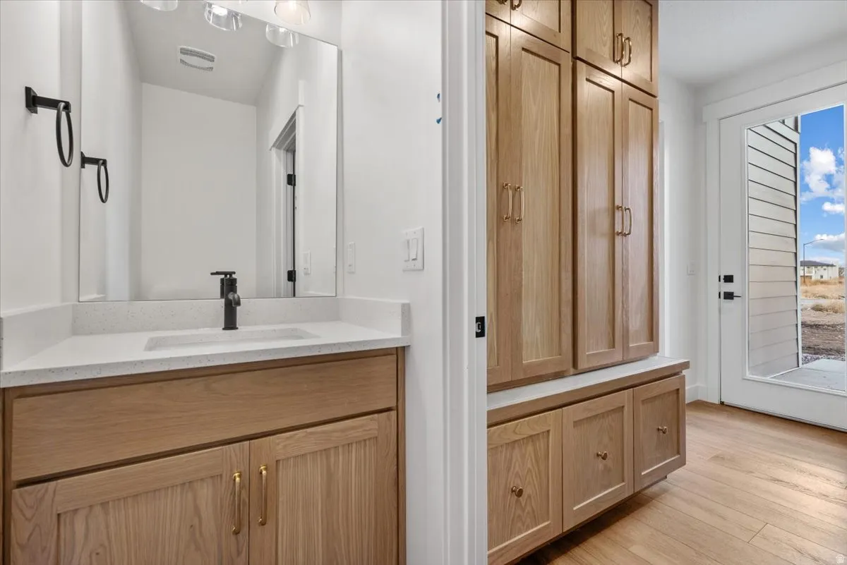 Vanity with wood-finish cabinetry, white countertop, and rectangular sink
