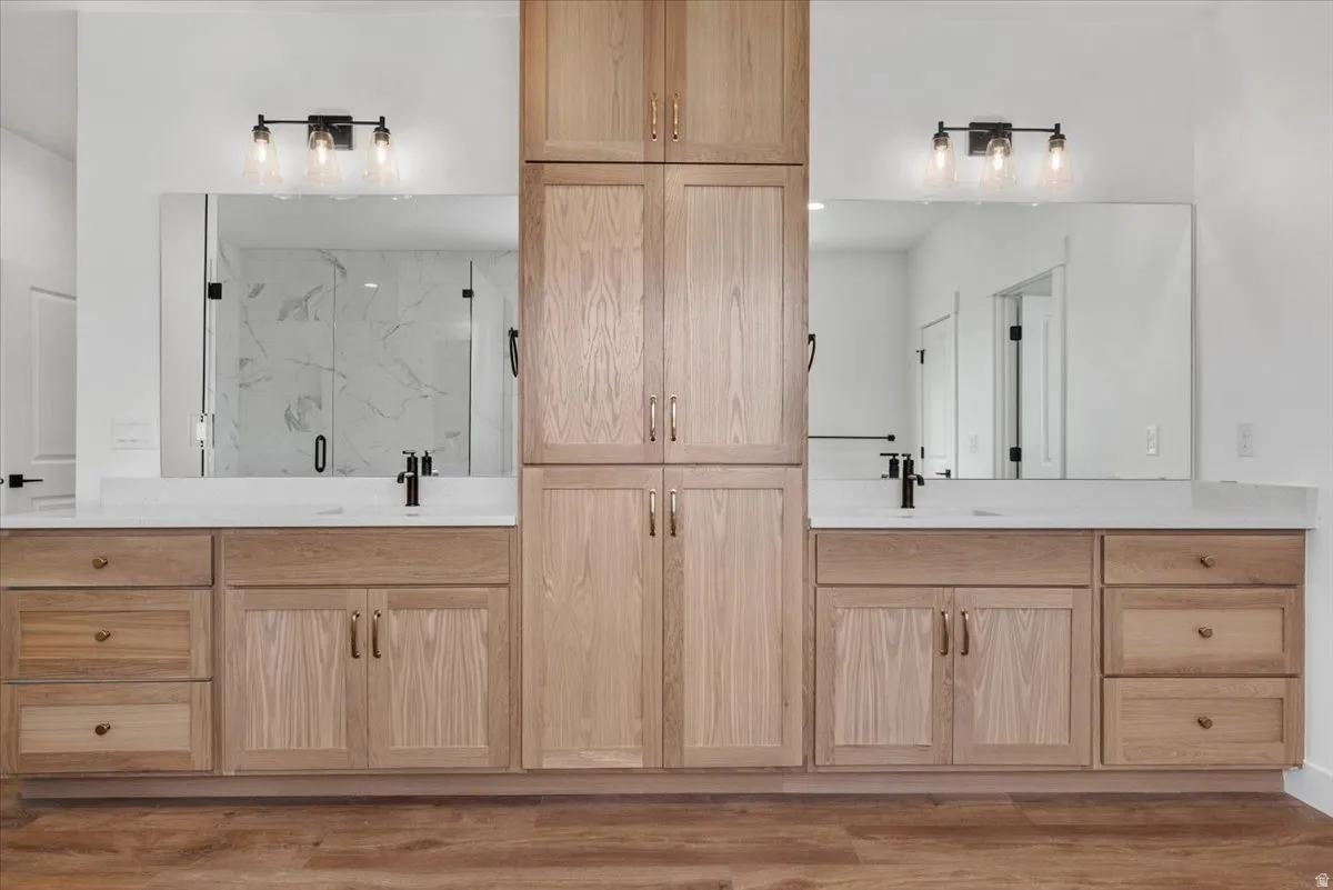 Dual vanities with integrated sinks, light wood-finish cabinetry, and matte black fixtures