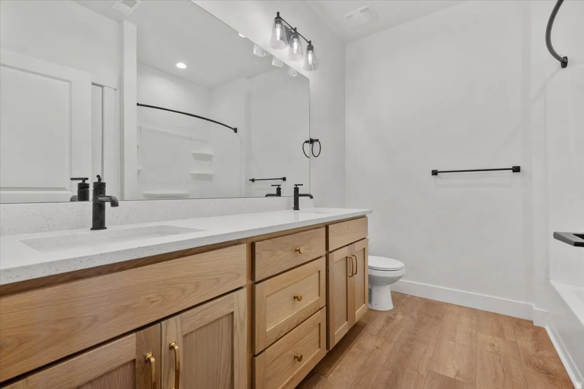 Dual vanity with light wood-finish cabinetry, white countertop, and matte black fixtures