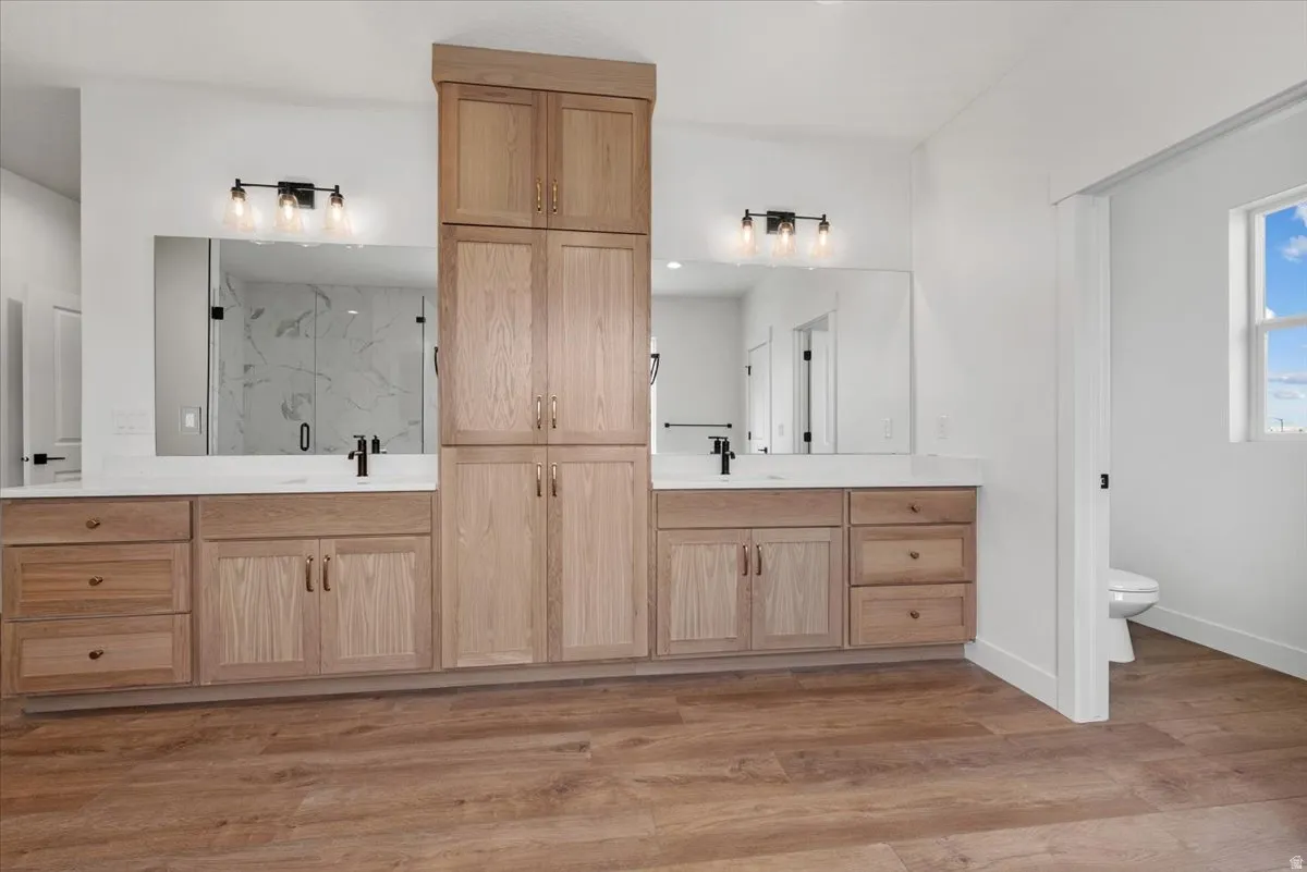 Dual vanities with white countertops, wood-finish cabinetry, and black fixtures