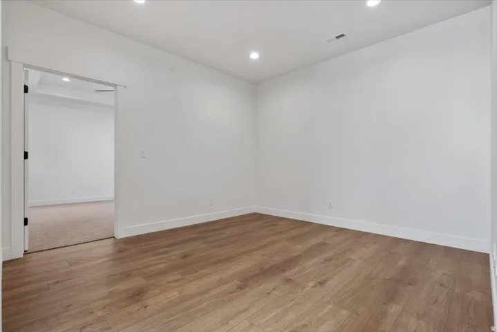 Wood-finish flooring, recessed ceiling lighting, crisp white walls, and a white trim package