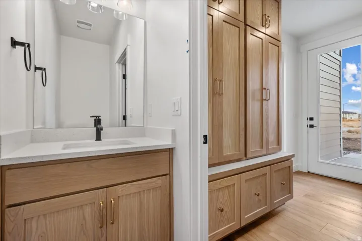 Vanity with wood-finish cabinetry, white countertop, and rectangular sink