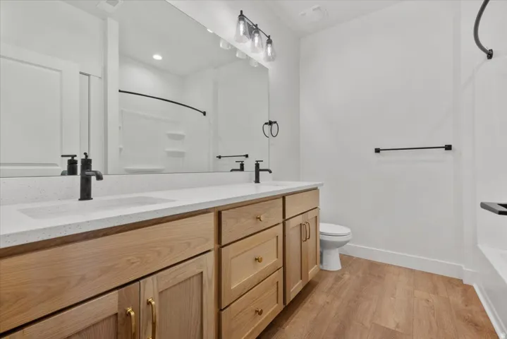 Dual vanity with light wood-finish cabinetry, white countertop, and matte black fixtures