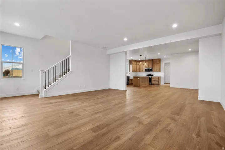 Wood-finish flooring throughout, white painted walls, recessed lighting, and a staircase with white risers and dark balusters