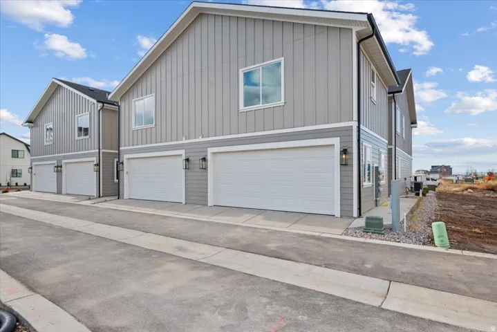 Modern exterior featuring gray siding, white trim, attached garages, and exterior lighting fixtures