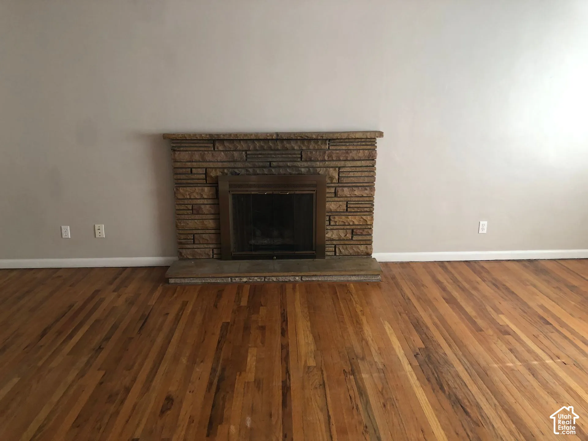 Warm wood-finish flooring with a stone-clad fireplace and hearth
