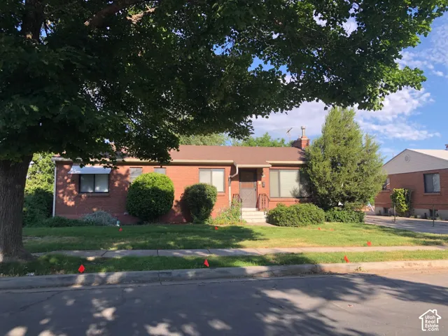 Brick exterior residence with a shingle roof, mature front yard tree, and established landscaping