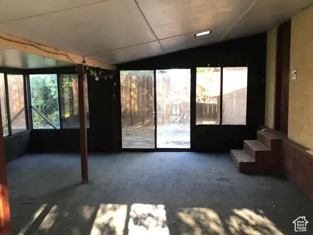 Enclosed outdoor space featuring multiple window panels, a vaulted ceiling, and built-in steps