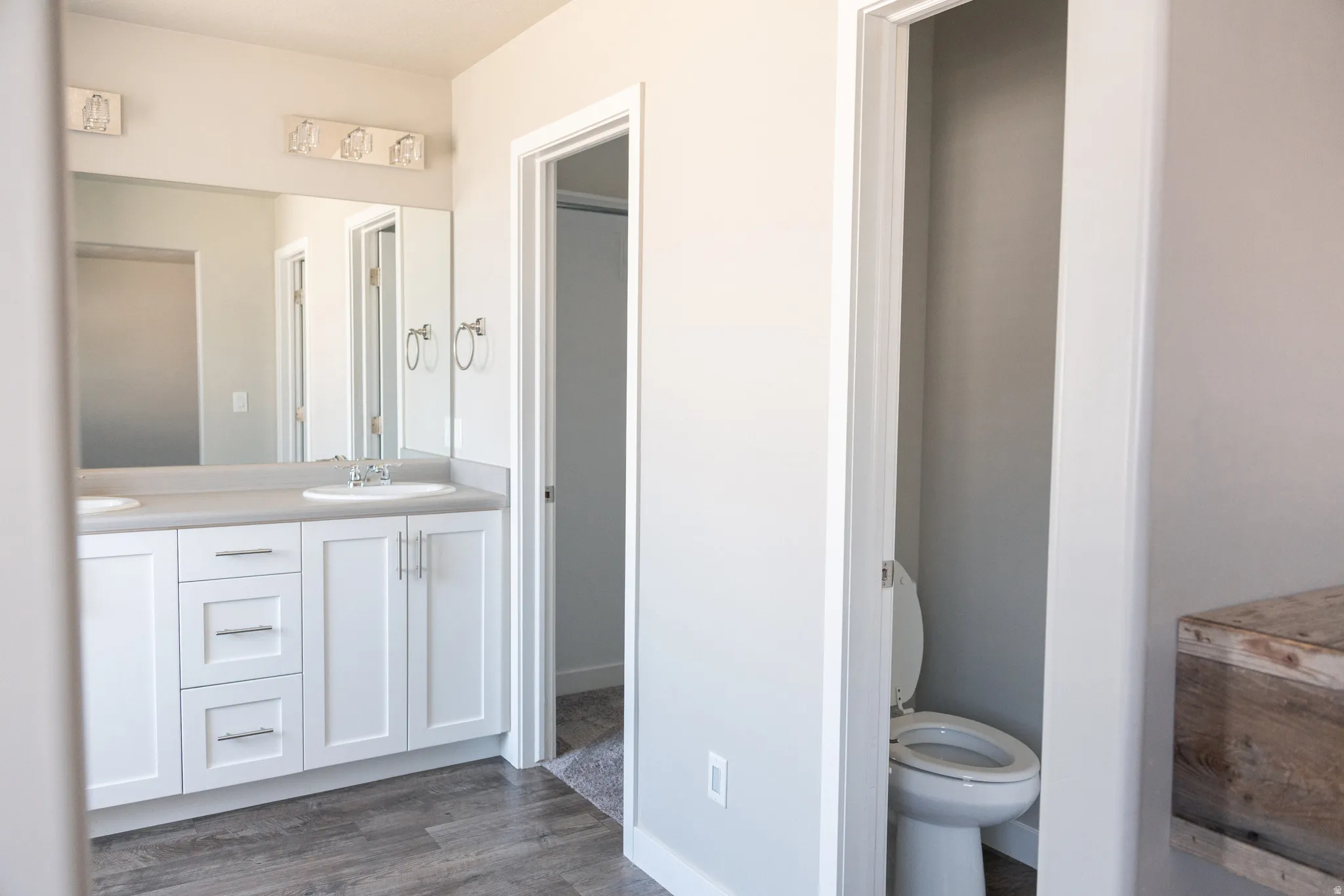 Spa-inspired primary bathroom featuring a dual-sink vanity with white cabinetry, brushed nickel hardware, and an expansive mirror with integrated lighting