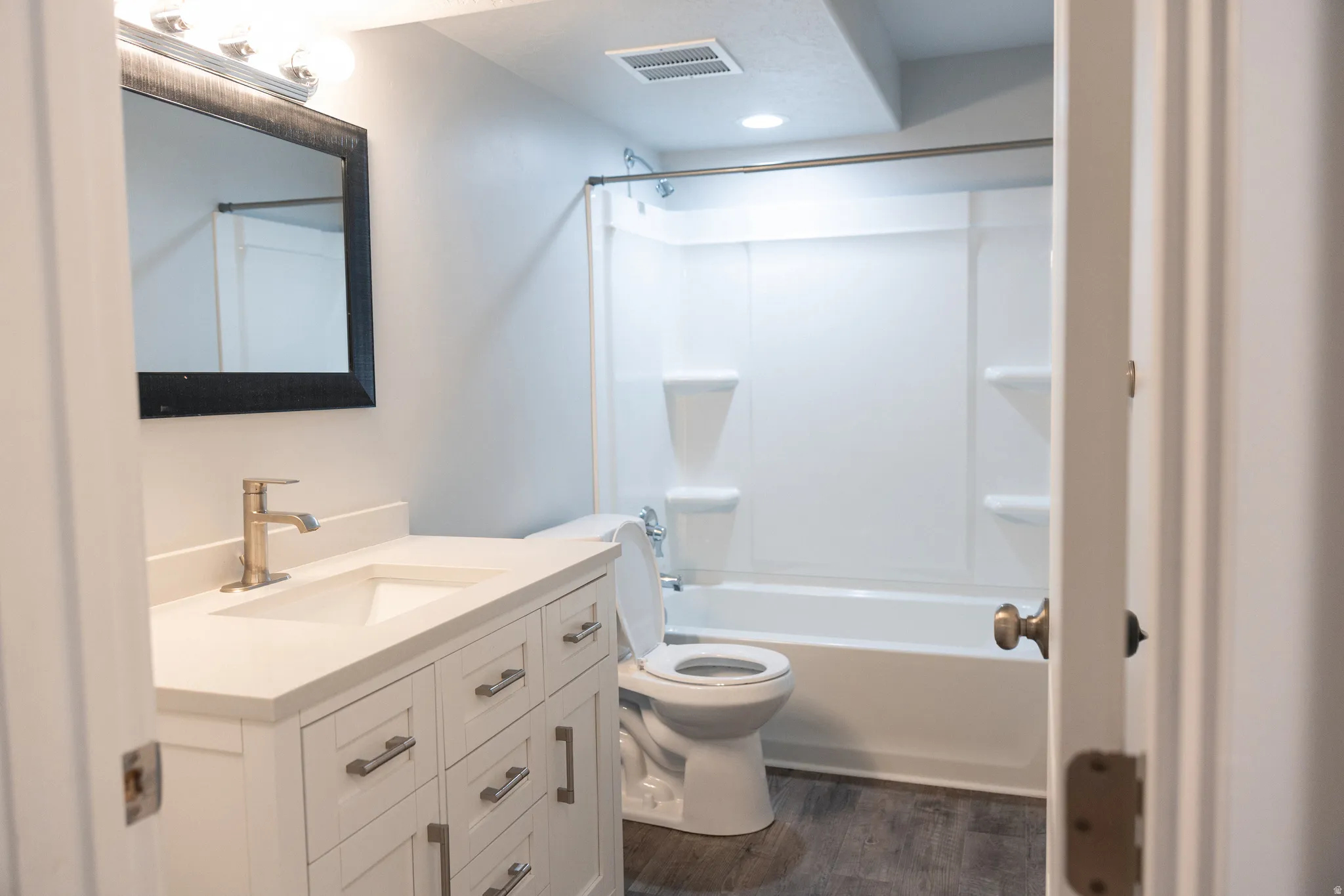 Spa-inspired bathroom featuring a custom white vanity with multiple drawers and brushed gold hardware, quartz countertop, vessel sink, and framed mirror with integrated lighting