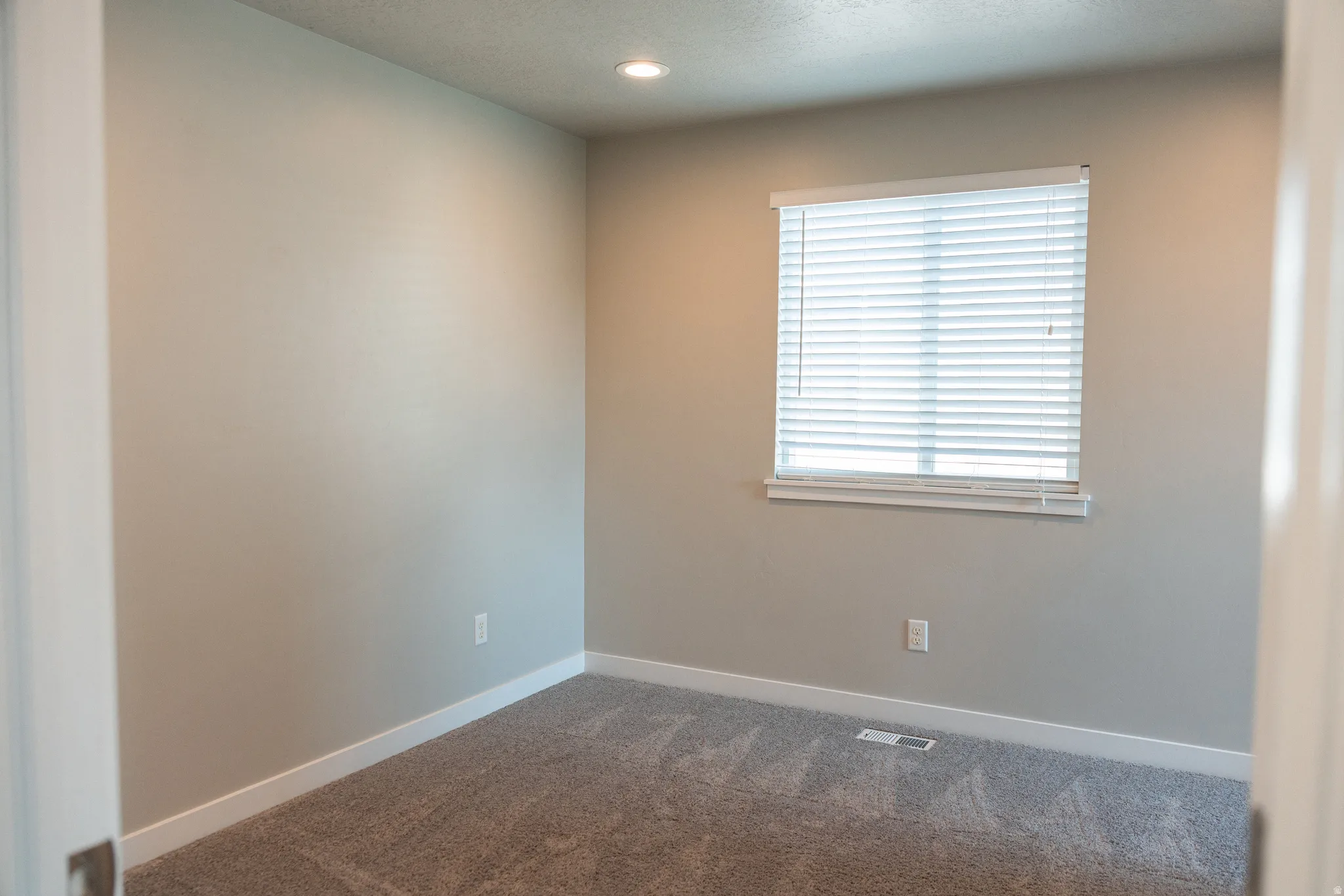 Recessed lighting, neutral wall paint, white trim, window with blinds, and carpeted flooring