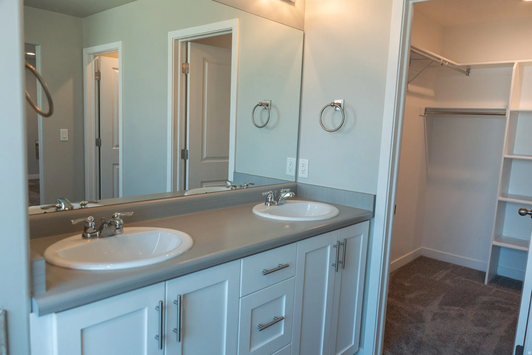 Dual vanity with white cabinetry and chrome hardware, featuring two undermount sinks and a neutral-toned countertop