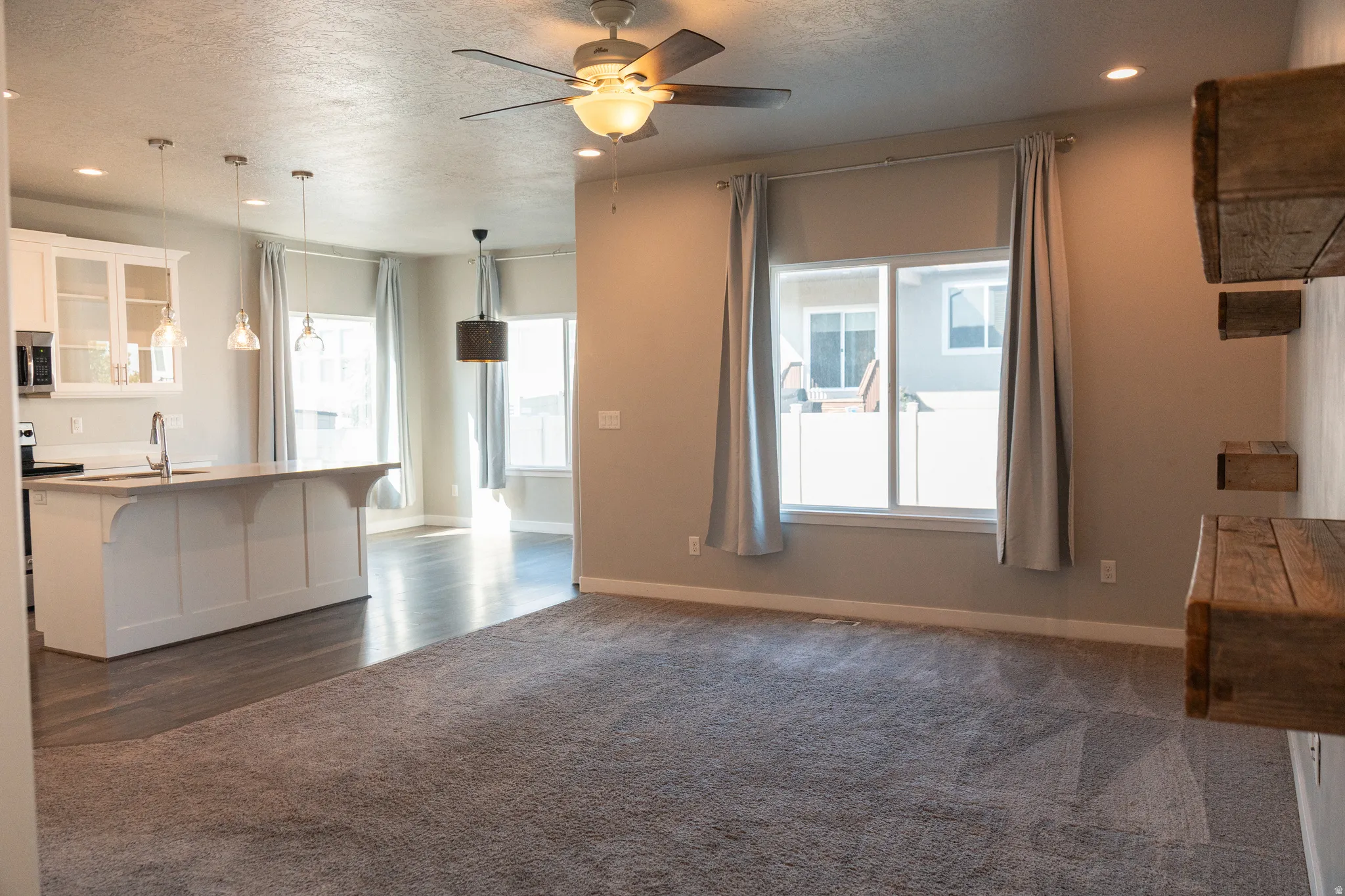 Open-concept living area featuring hardwood-finish flooring, recessed ceiling lighting, and a ceiling fan with integrated light fixture