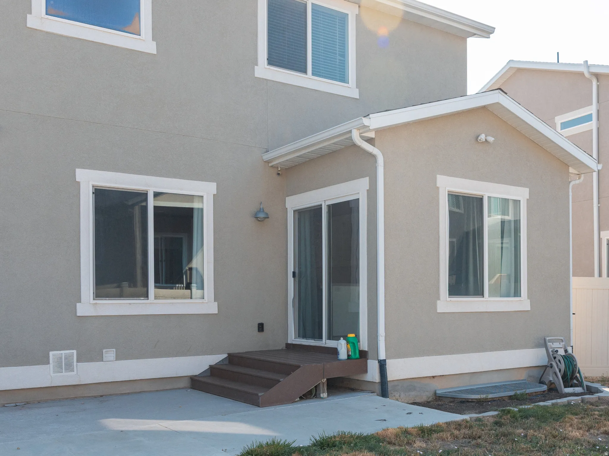 Rear exterior featuring a concrete patio, sliding glass door, and a vinyl fence