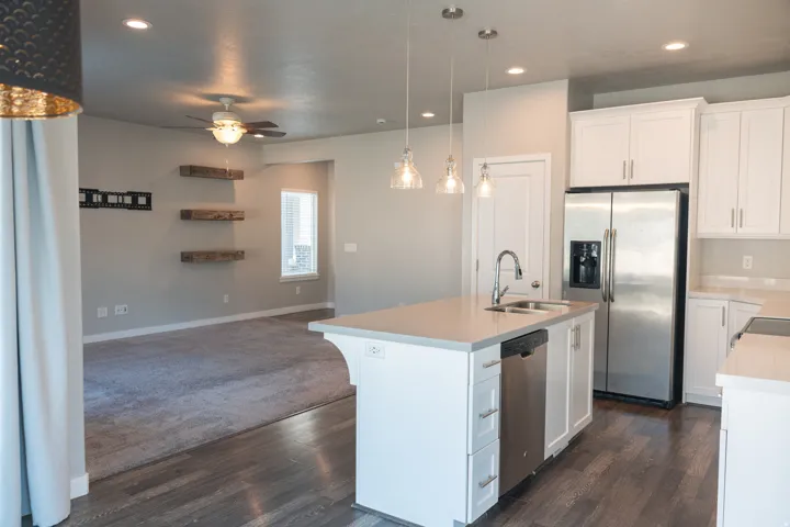 Open-concept living space with a kitchen island, stainless steel appliances, white cabinetry, wood-finish flooring, and recessed lighting