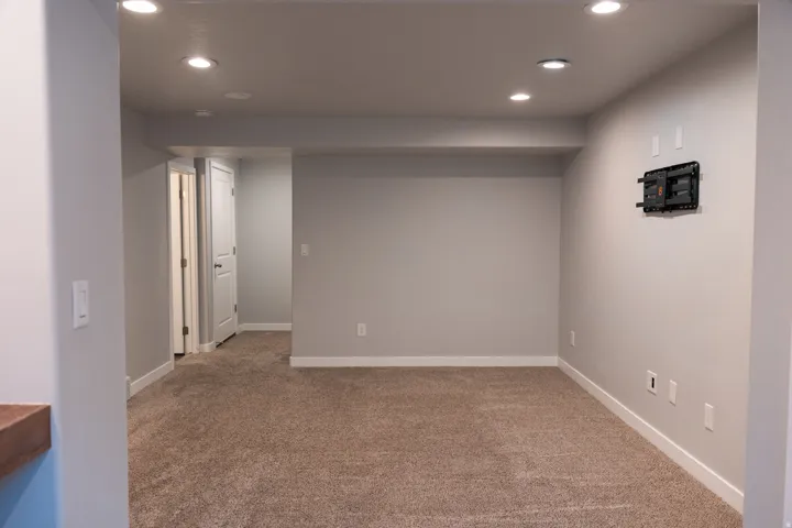 Recessed lighting, light gray wall paint, white trim, and a wall-mounted television bracket