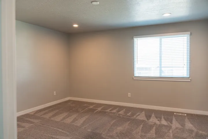 Recessed lighting, neutral wall tones, window with horizontal blinds, carpeted flooring with geometric pattern