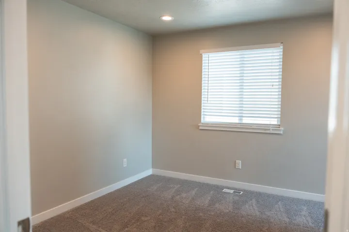 Recessed lighting, neutral wall paint, white trim, window with blinds, and carpeted flooring