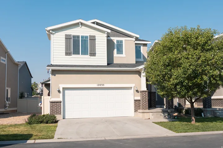 Two-story residence featuring a two-car garage, brick accents, and a concrete driveway