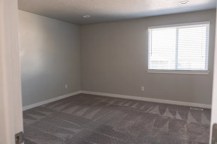Neutral wall color, recessed lighting, window with blinds, and patterned carpet
