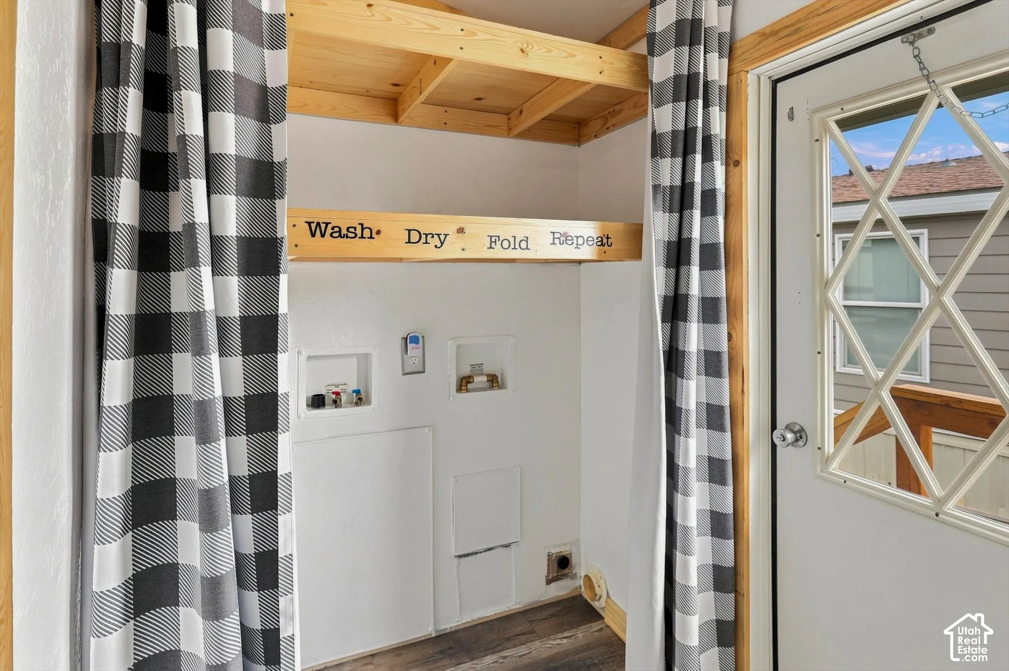 Laundry area featuring a utility hookup, overhead wood shelving, and wood-finish flooring
