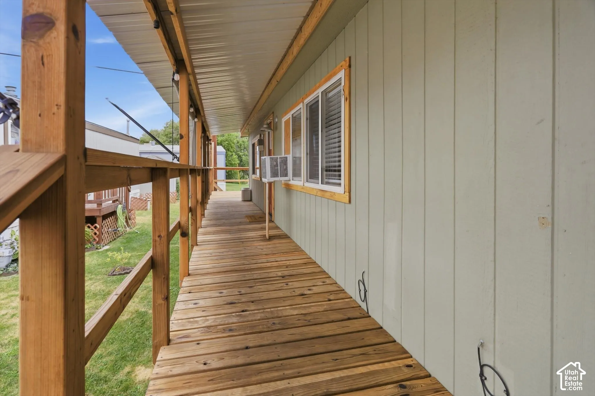 Expansive wood-plank deck with a covered area, wood railings, and board-and-batten siding