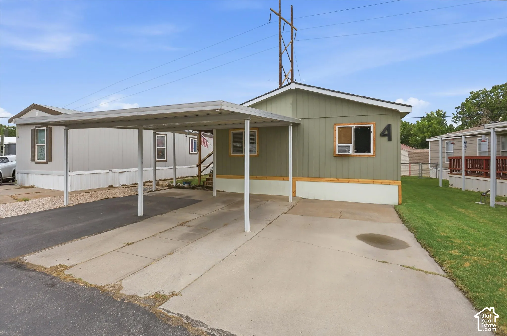 Carport structure, concrete driveway, siding exterior, number "4" address marker, green lawn