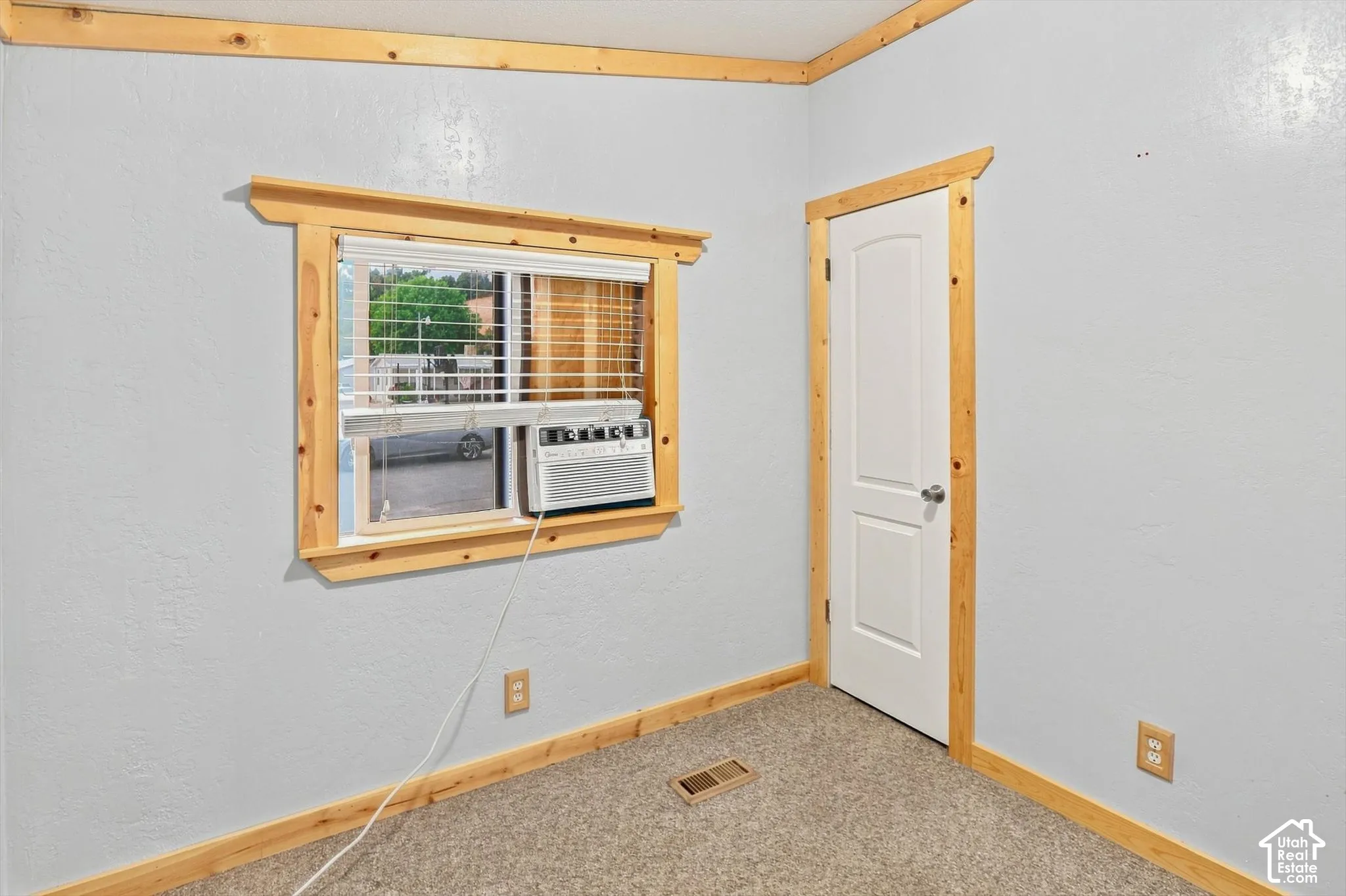 Window with blinds, wood-finish trim, and light gray wall paint