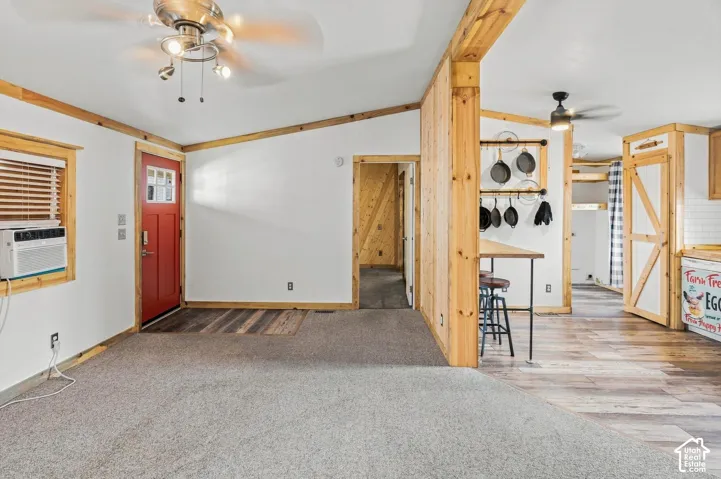 Wood-finish flooring, accent wood-paneled walls, and a recessed ceiling fan with integrated lighting