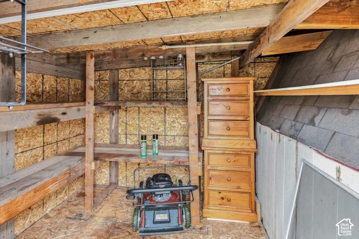 Interior storage area featuring wood-finish paneling, exposed wood structural beams, and built-in wood shelving