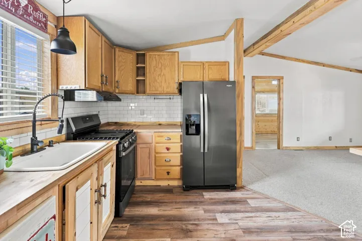 Kitchen featuring wood-finish flooring, wood cabinetry, white subway tile backsplash, and dark-finish appliances