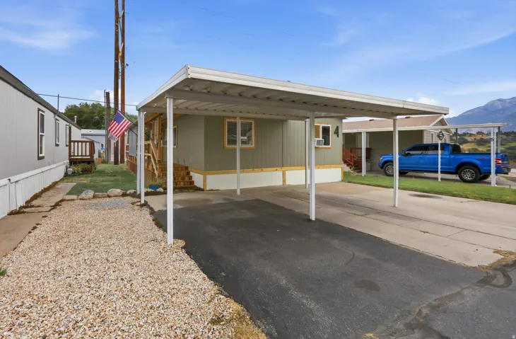 Carport with paved driveway, gravel landscaping, and wooden exterior stairs