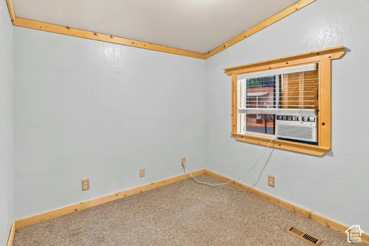 Carpet flooring, light-toned wall finish, wood-finish trim, and a window air conditioning unit